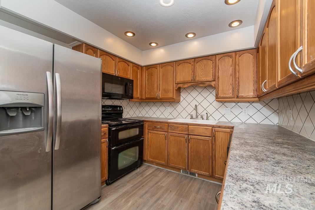 480 Easy Street Kuna, ID 83634 - Photo 30 of 39 Kitchen featuring black appliances, brown cabinetry, light countertops, and recessed lighting