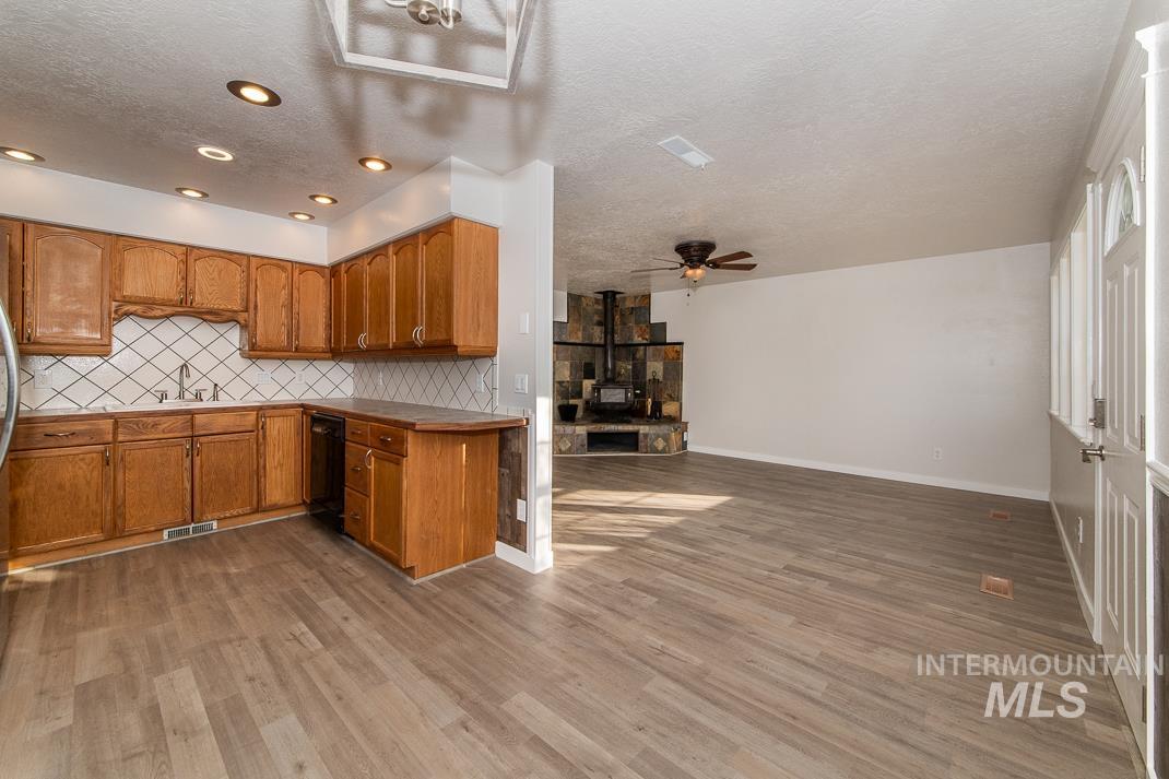 480 Easy Street Kuna, ID 83634 - Photo 39 of 39 Kitchen featuring a ceiling fan, a textured ceiling, open floor plan, brown cabinetry, and decorative backsplash