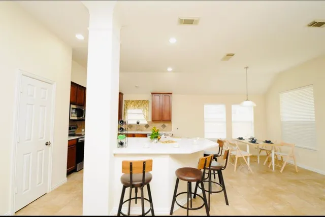 a dining hall with stainless steel appliances kitchen island granite countertop a table and chairs