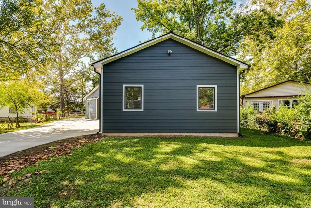 a view of a house with wooden fence next to a yard