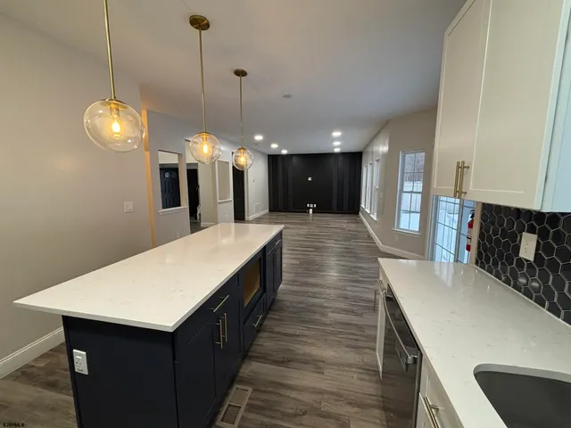a large kitchen with kitchen island a sink stainless steel appliances and a chandelier
