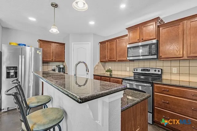 a kitchen with stainless steel appliances granite countertop a stove refrigerator sink and microwave