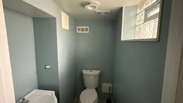 a white toilet sitting in a bathroom next to a window