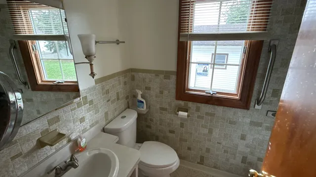 a bathroom with a granite countertop toilet a sink a mirror and a window