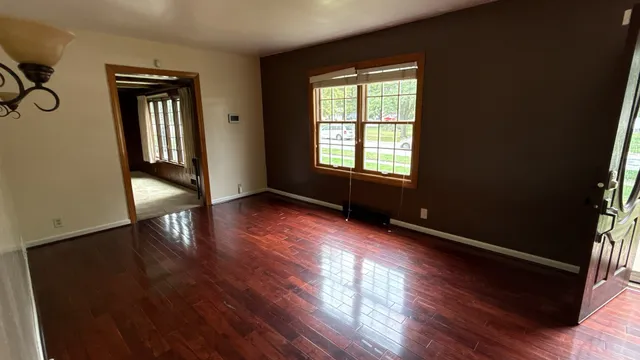 a view of an empty room with wooden floor and a window