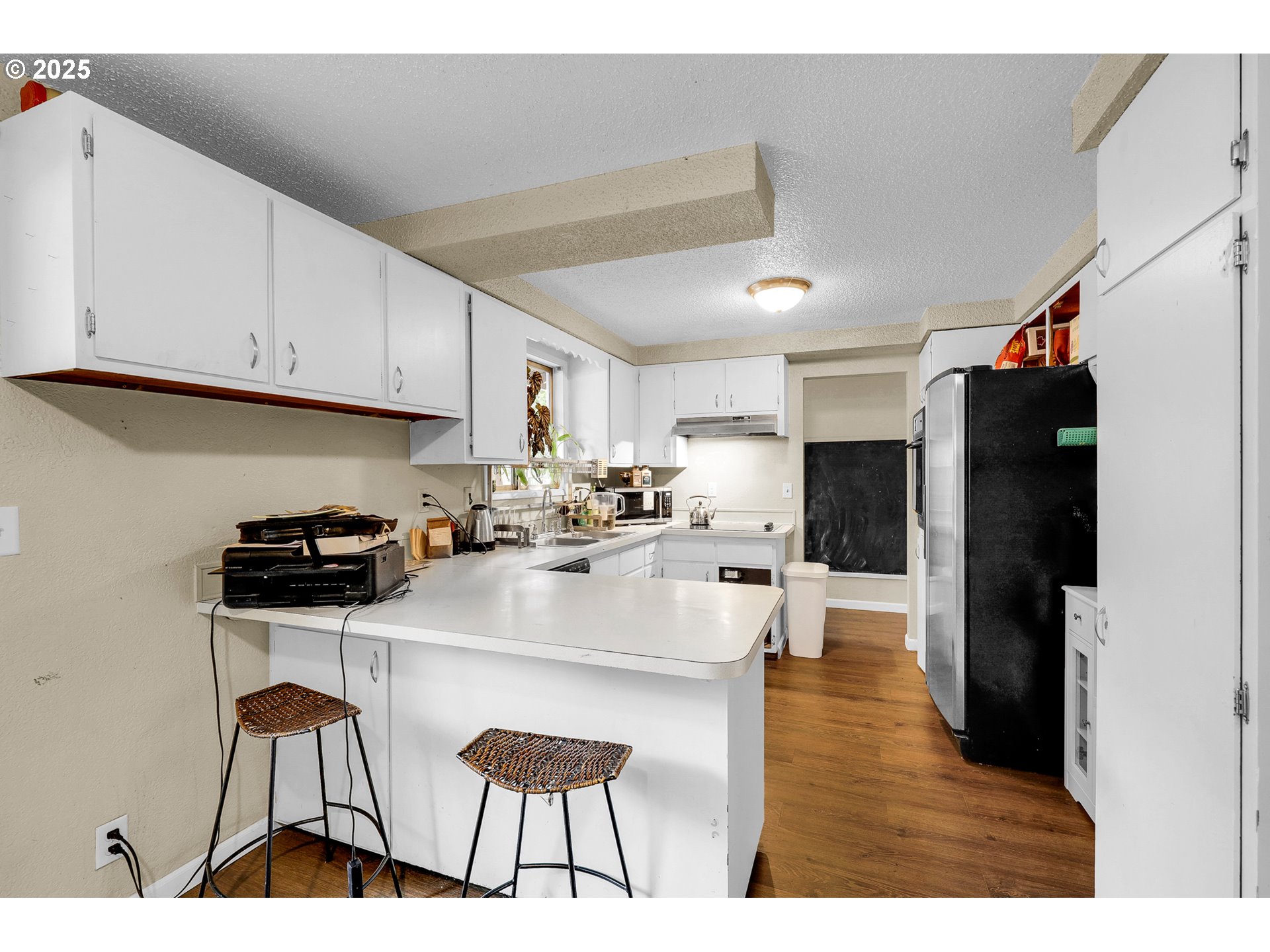 910 East 43rd Avenue Eugene, OR 97405 - Photo 12 of 47 a kitchen with stainless steel appliances kitchen island granite countertop a refrigerator a stove a sink and white cabinets with wooden floor