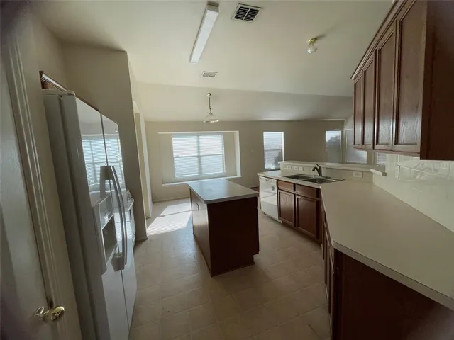 a kitchen with stainless steel appliances granite countertop a refrigerator a stove and a sink