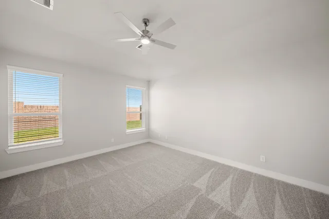 an empty room with windows and fan