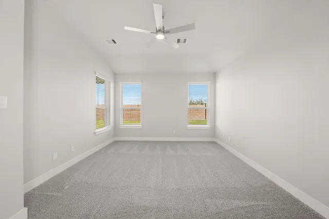 an empty room with windows and fan