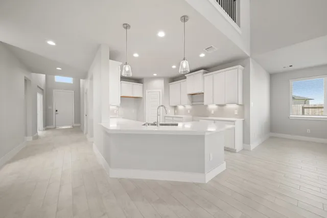 a large white kitchen with kitchen island a sink a center island stainless steel appliances and a fireplace