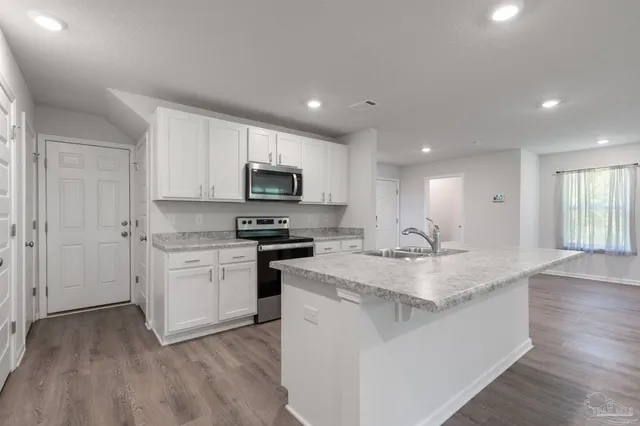 a kitchen with stainless steel appliances granite countertop a sink dishwasher stove top oven and refrigerator