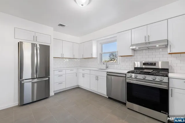 a kitchen with cabinets stainless steel appliances and wooden floor