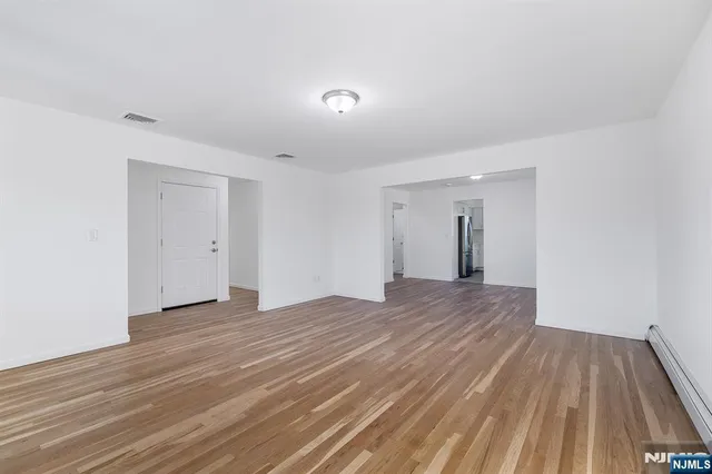 a view of an empty room with wooden floor and closet
