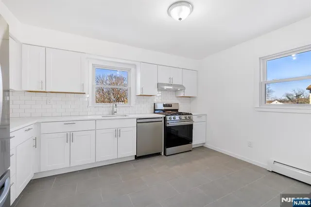 a kitchen with granite countertop white cabinets and stainless steel appliances