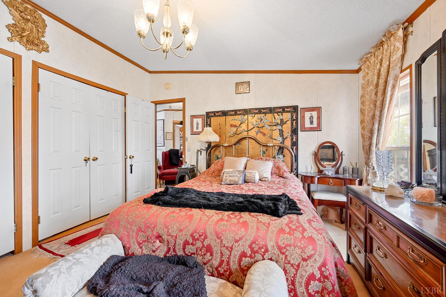 4400 Murray Hollow Road Thaxton, VA 24174 - Photo 17 of 56 a bedroom with a bed and a chandelier
