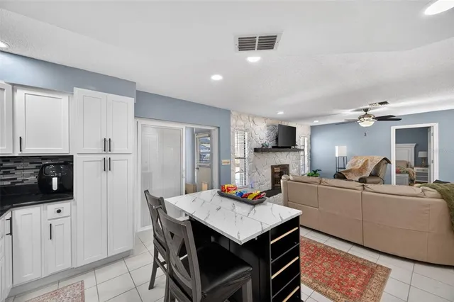 a kitchen with stainless steel appliances kitchen island granite countertop a dining table chairs refrigerator and sink