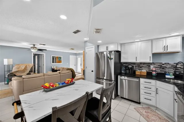 a kitchen with a refrigerator a stove a sink dishwasher and white cabinets with wooden floor