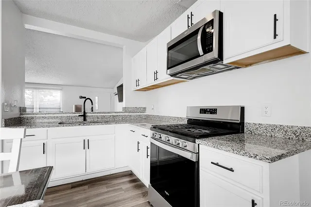 a kitchen with granite countertop cabinets stainless steel appliances and a sink