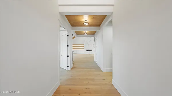 a view of a hallway with wooden floor and a bathroom
