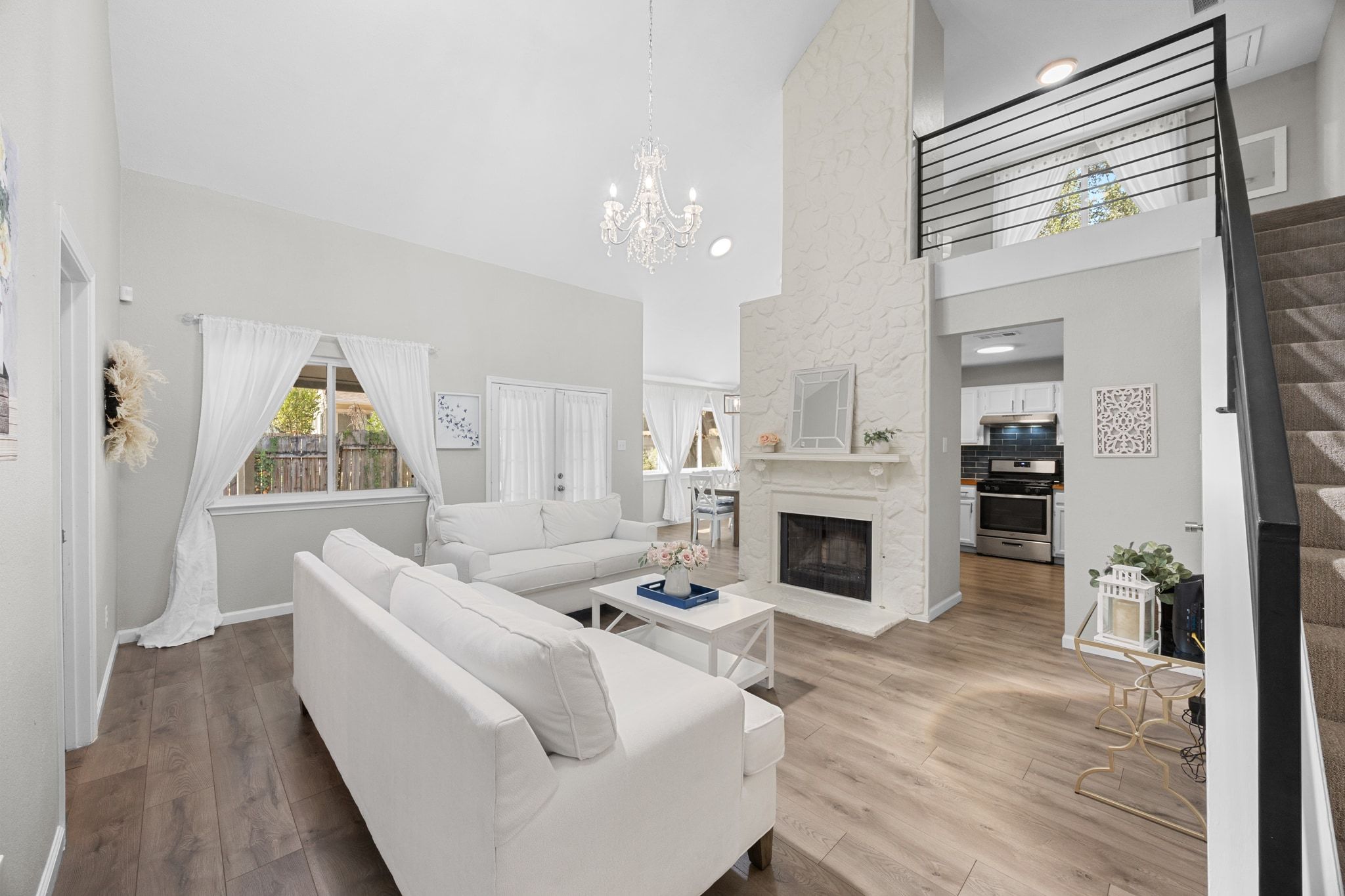 6305 Weeks Cove Austin, TX 78727 - Photo 4 of 30 Living room featuring a high end fireplace, wood finished floors, a high ceiling, a chandelier, and stairway