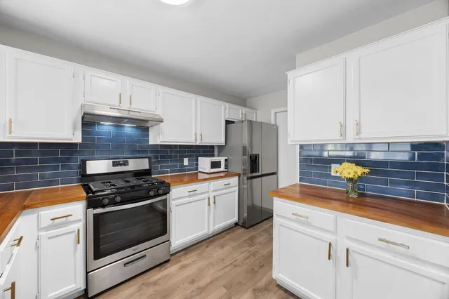 a kitchen with stainless steel appliances white cabinets and a stove top oven