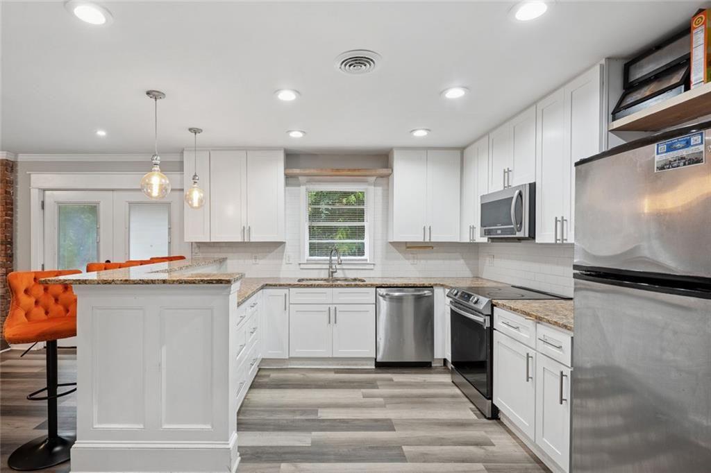 4136 Weelaunee Road Ellenwood, GA 30294 - Photo 8 of 22 a kitchen with stainless steel appliances granite countertop a sink and dishwasher a stove top oven with wooden floor