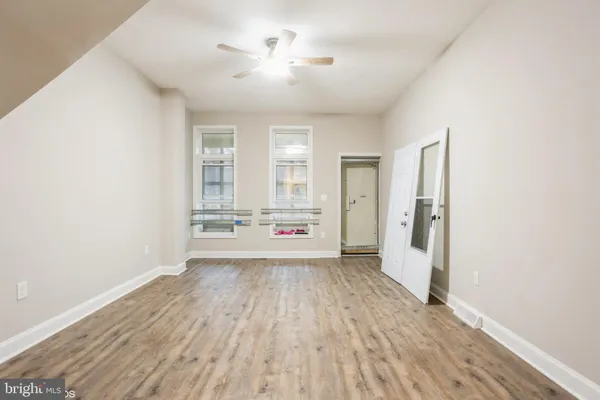 a view of a room with a hardwood floor and a ceiling fan