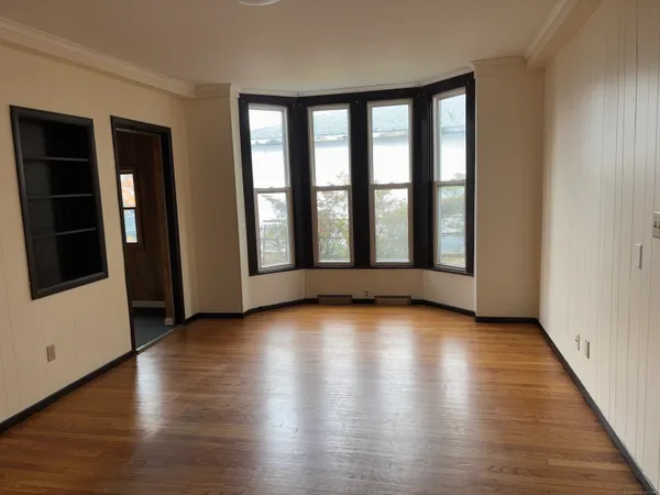 a view of an empty room with wooden floor and a window