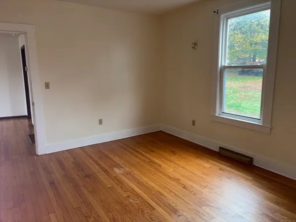 a view of an empty room with a window and wooden floor