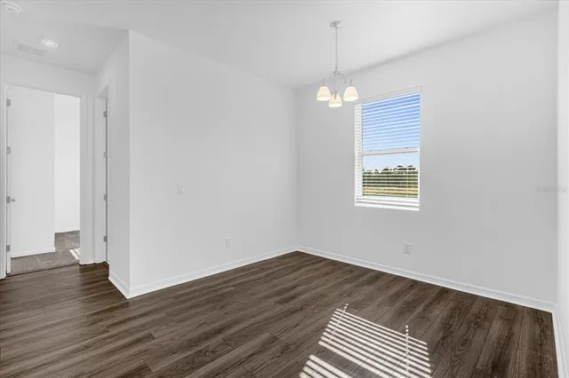 an empty room with wooden floor cabinet and windows