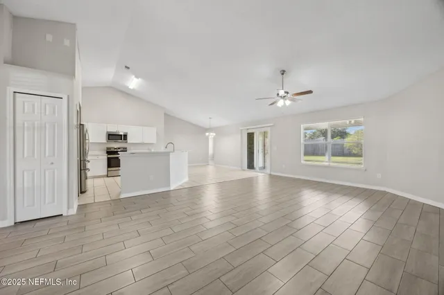 a view of an empty room with window and wooden floor