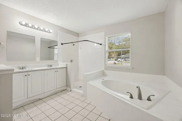 a spacious bathroom with a tub sink and mirror