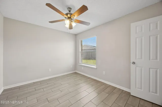 an empty room with a window and ceiling fan