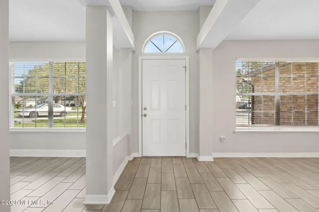 an empty room with wooden floor cabinet and windows