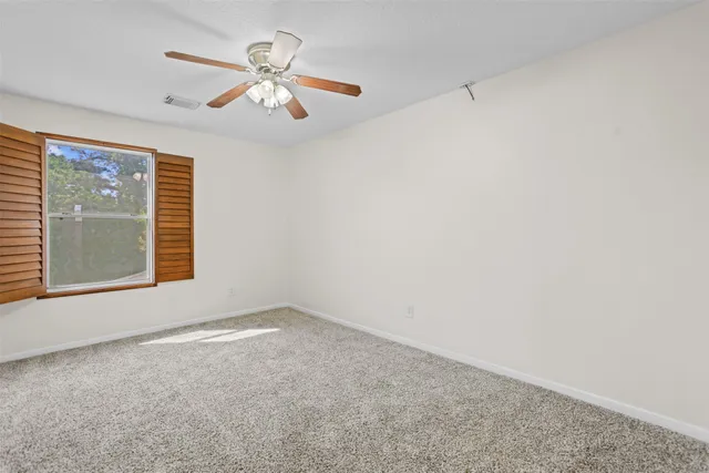 an empty room with a window and a ceiling fan