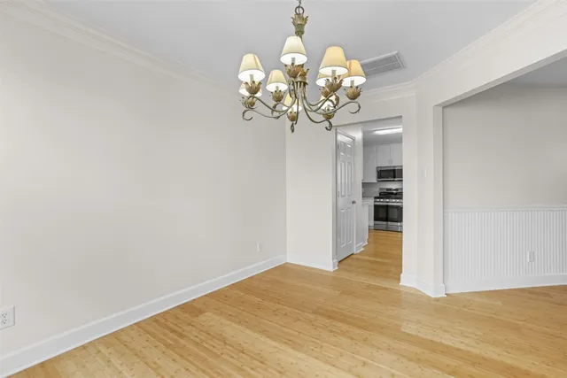 a view of a room with wooden floor and chandelier