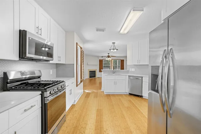 a kitchen with stainless steel appliances a refrigerator sink and white cabinets
