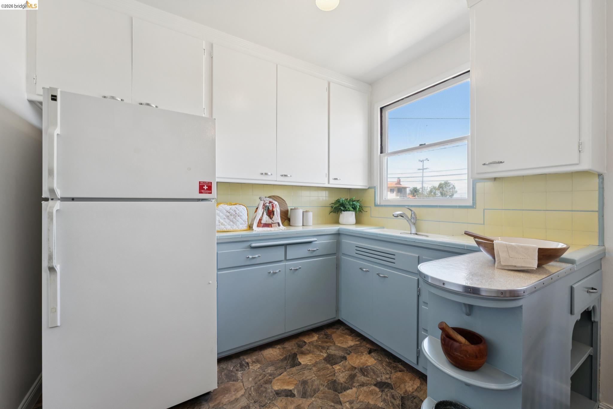 15162 Inverness Street San Leandro, CA 94579 - Photo 10 of 25 Kitchen featuring light blue lower cabinetry, white upper cabinetry, and a yellow tiled backsplash