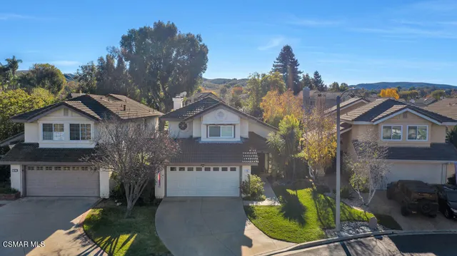 a view of a house with a small yard and a large tree in it