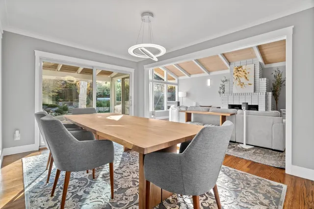 a dining room with wooden floor a chandelier a wooden table and chairs