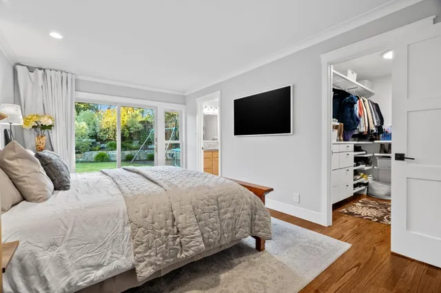 a bedroom with a bed a flat screen tv and a large window