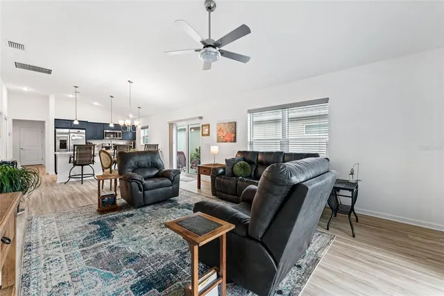 a kitchen with stainless steel appliances granite countertop a sink a stove a refrigerator cabinets a dining table and chairs