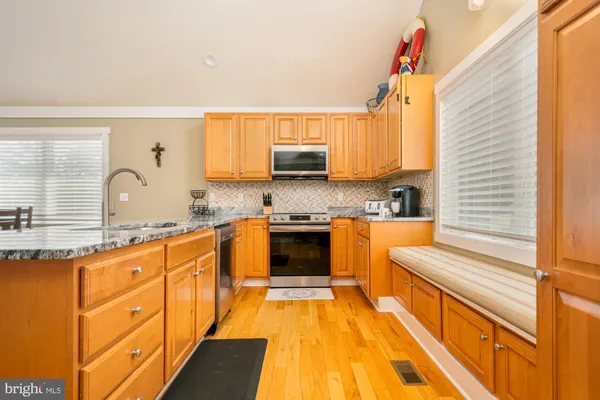 a view of living room with granite countertop kitchen island stainless steel appliances wooden floor and living room view