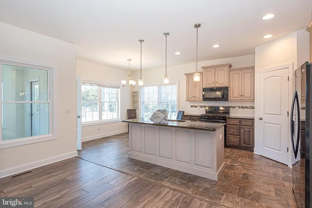 a kitchen with stainless steel appliances granite countertop a refrigerator a sink dishwasher a stove and white cabinets with wooden floor