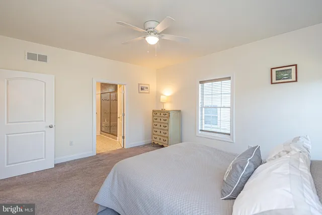 a spacious bedroom with a bed a dresser and a window