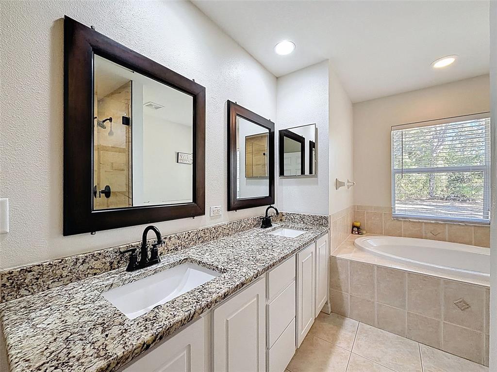 12105 Maripoe Road Weeki Wachee, FL 34614 - Photo 32 of 62 a bathroom with a granite countertop double vanity sink and mirror with bathtub