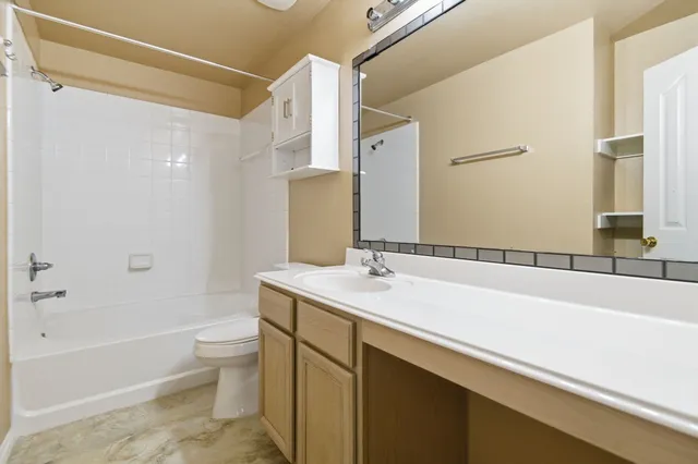 a bathroom with a bathtub sink vanity mirror and toilet