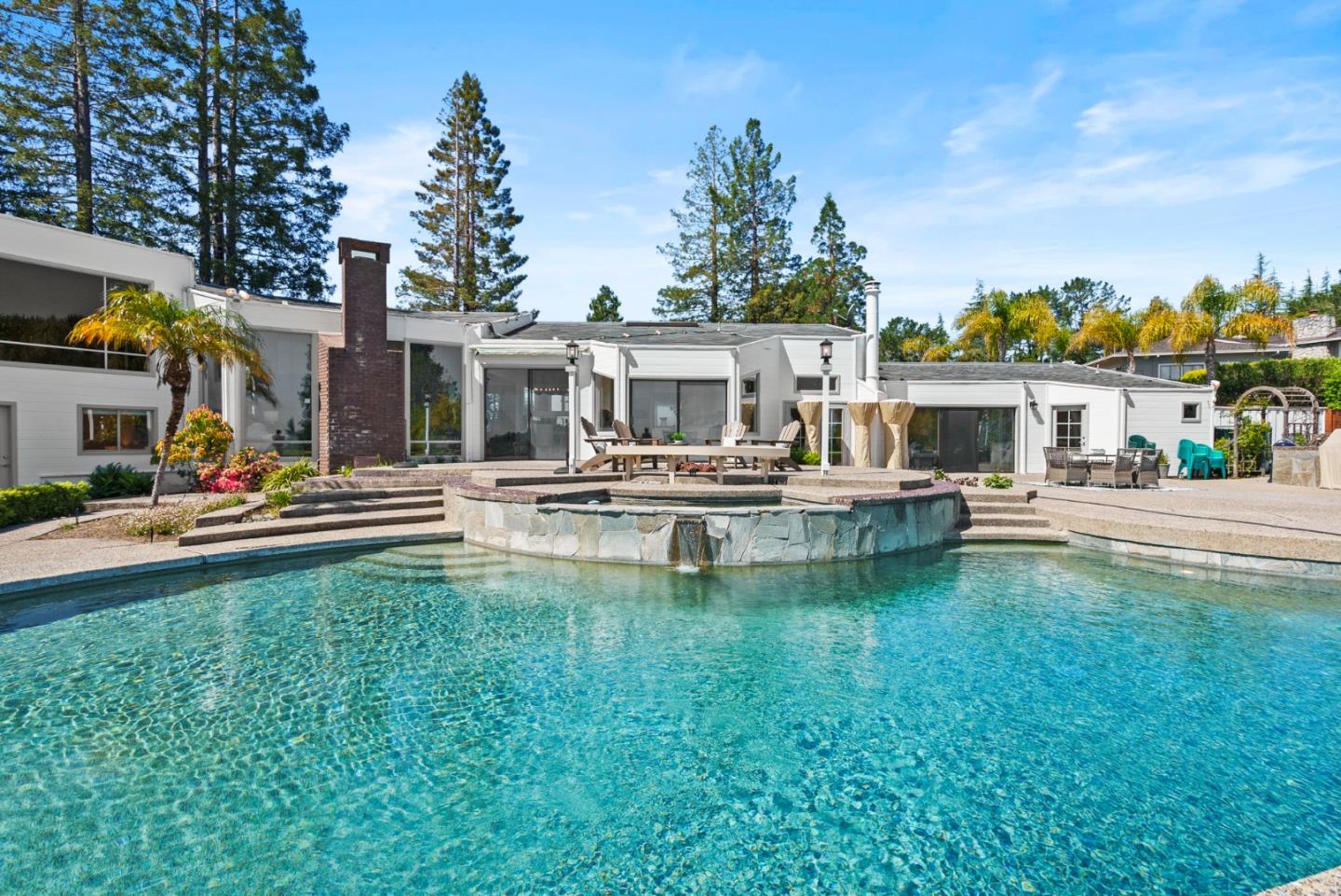 a swimming pool view with a seating space and a garden view