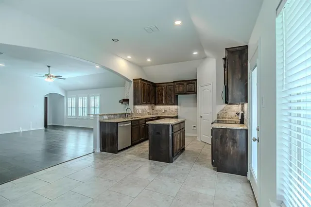 a large kitchen with a stove a sink dishwasher a refrigerator and a stove with wooden floor