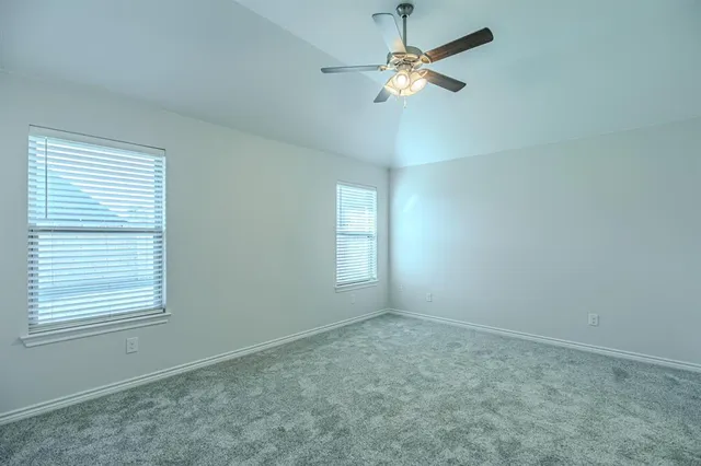 an empty room with windows and fan